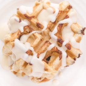 Cinnamon roll waffles topped with cream cheese glaze.