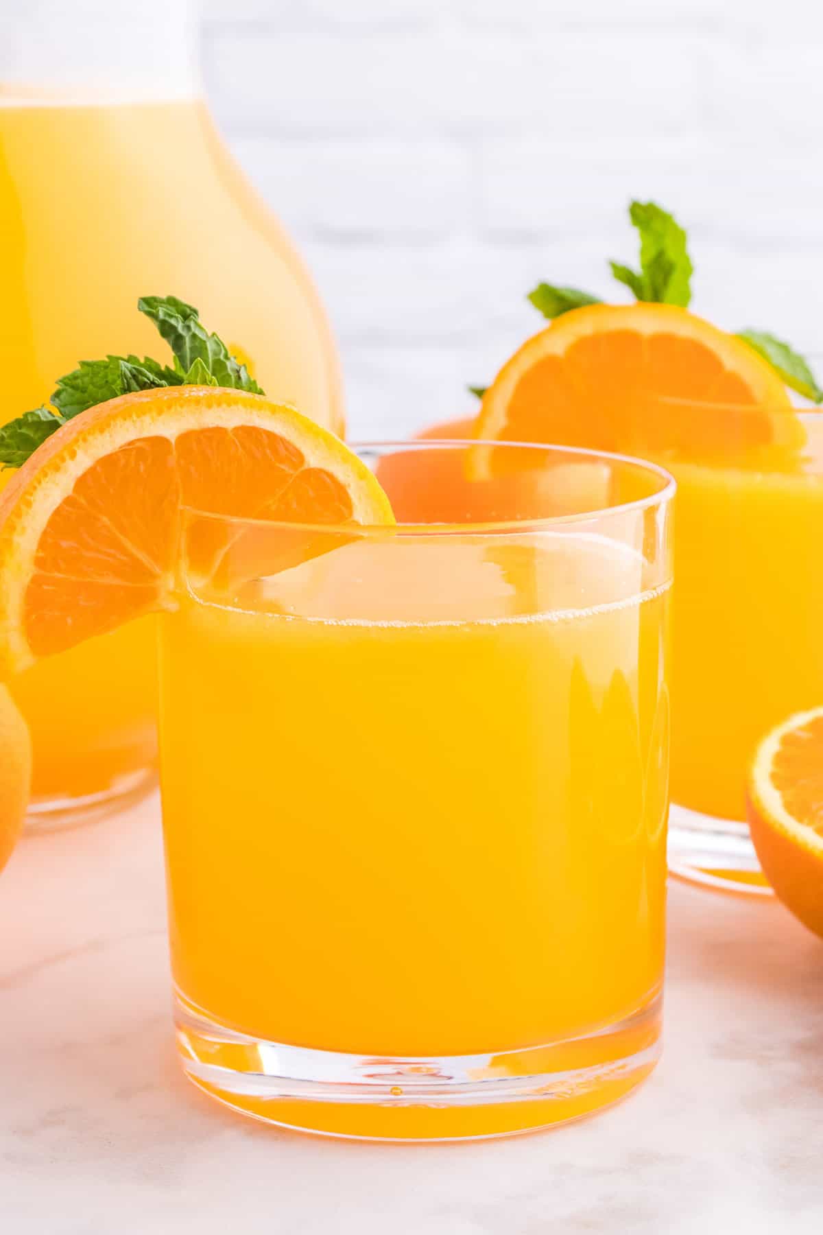 Homemade orangeade garnished with orange slice and mint.