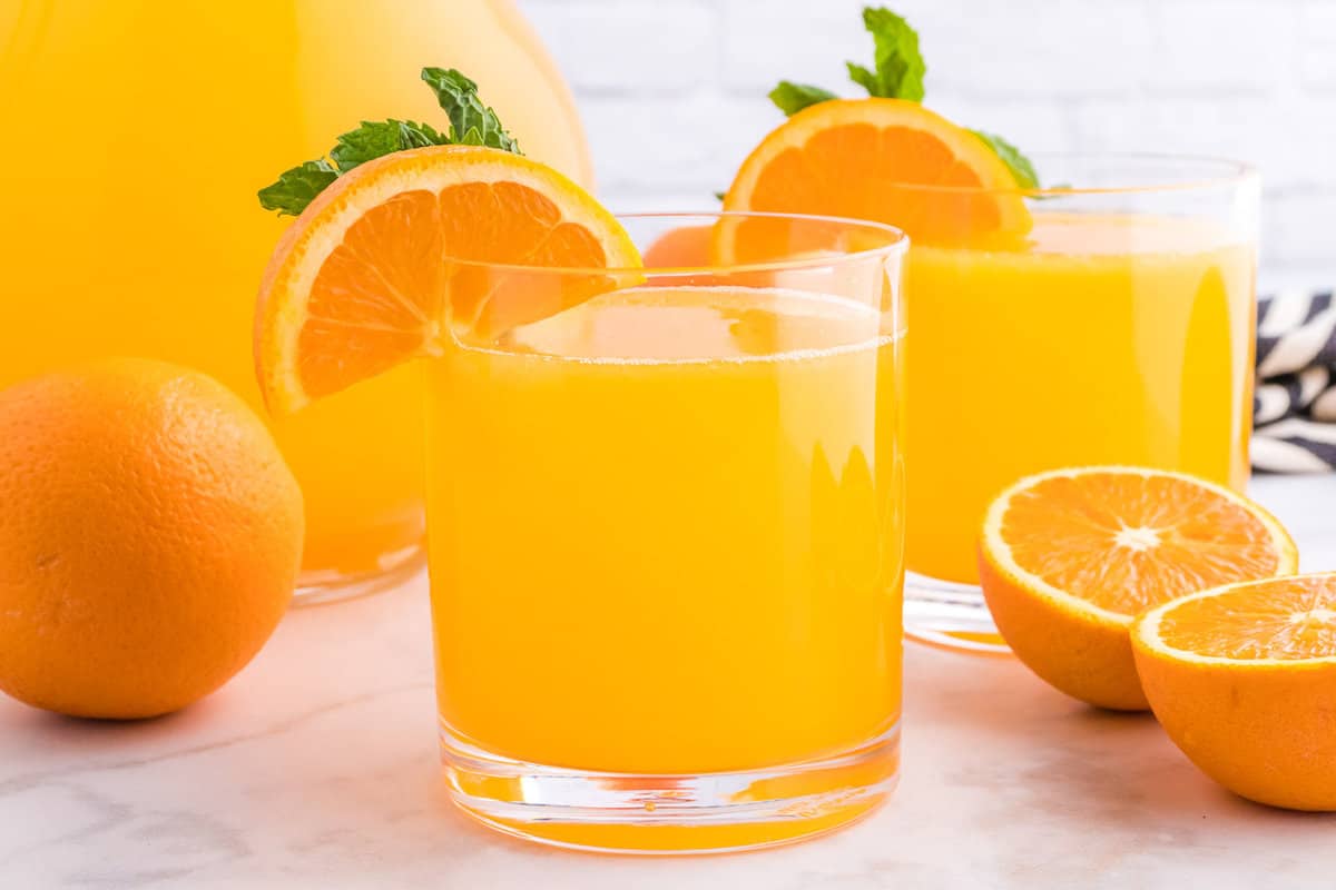 Orange beverage in a short glass, another in background.