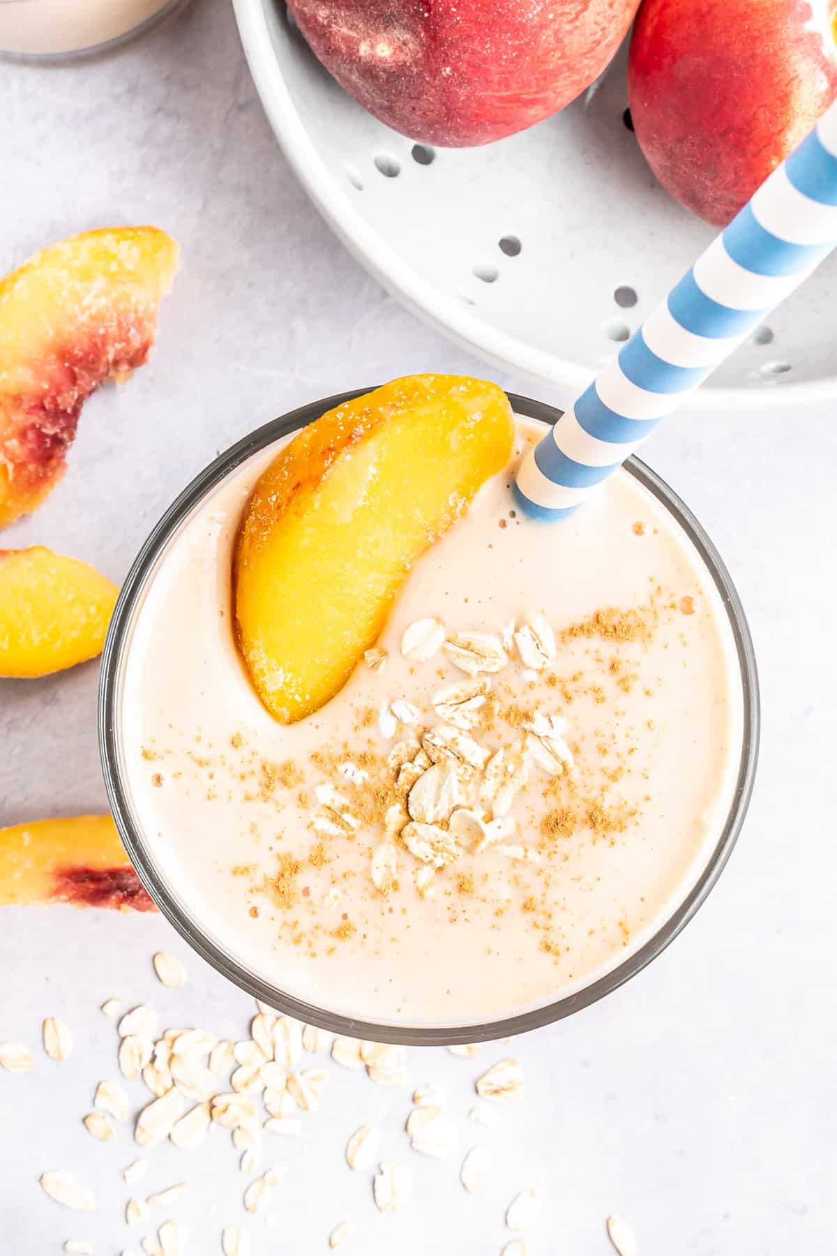 Peach smoothie garnished with peach and oats.