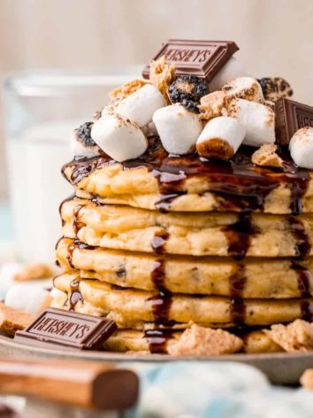 S'mores pancakes topped with marshmallows, chocolate syrup, and graham crackers.