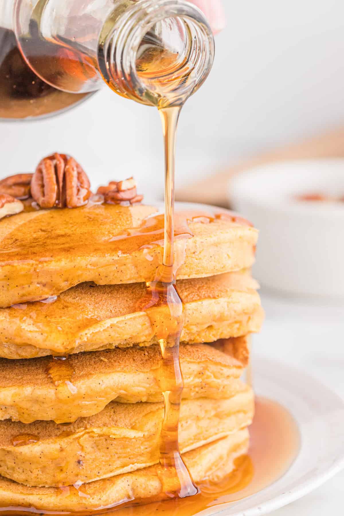 Sweet potato pancakes being drizzled with maple syrup.