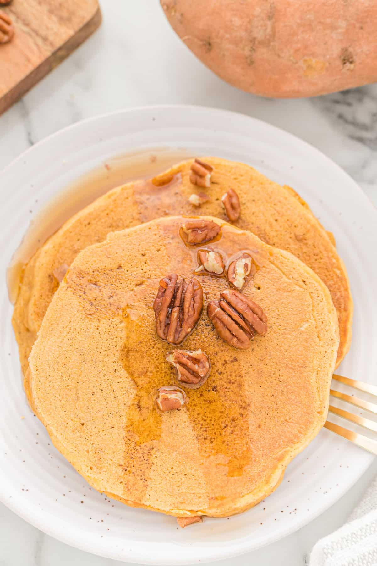 Light orange pancakes with maple syrup and pecans.