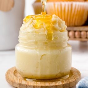 Homemade honey butter with honey being poured on it.