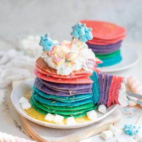 Unicorn pancakes with whipped cream and sprinkles.
