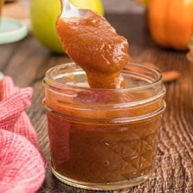Homemade apple butter in a small jar with spoon.