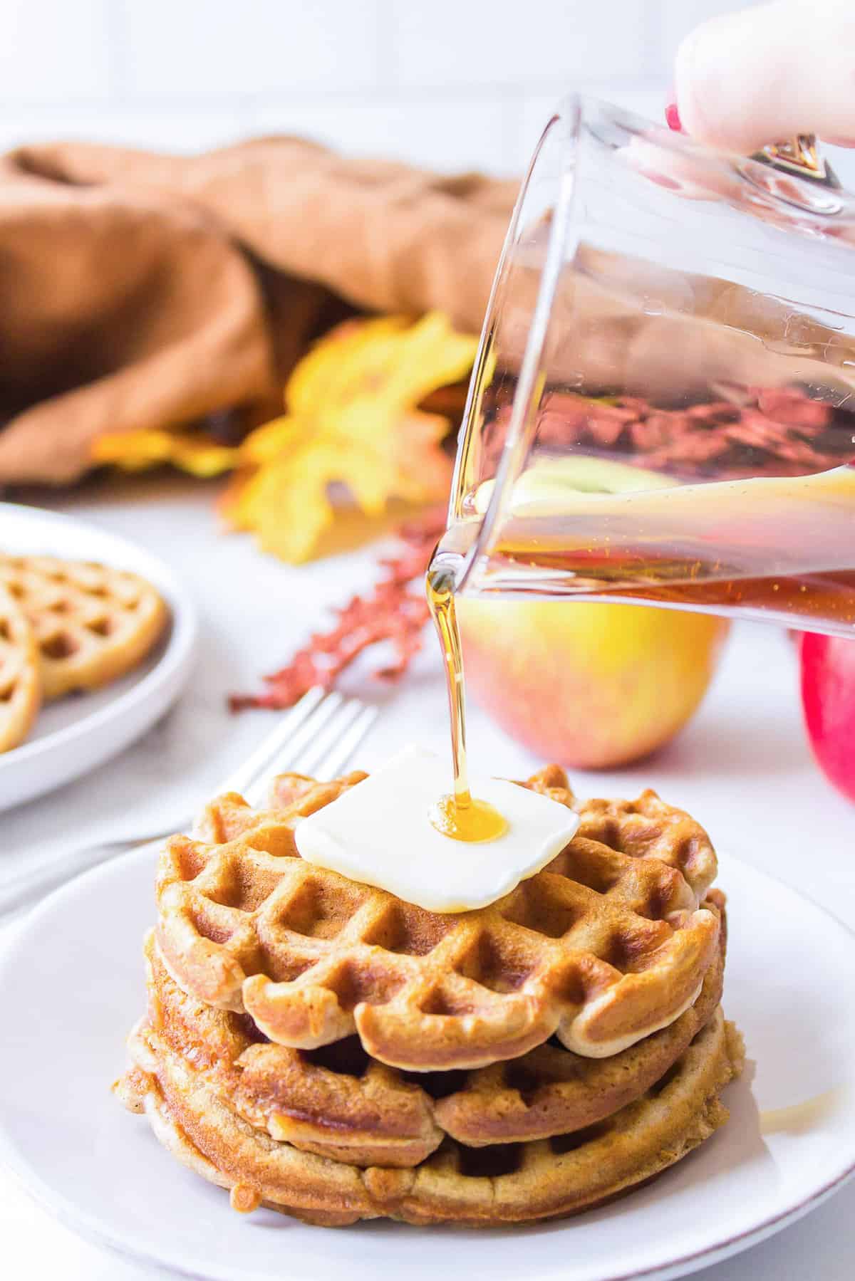 Syrup being poured on waffles.