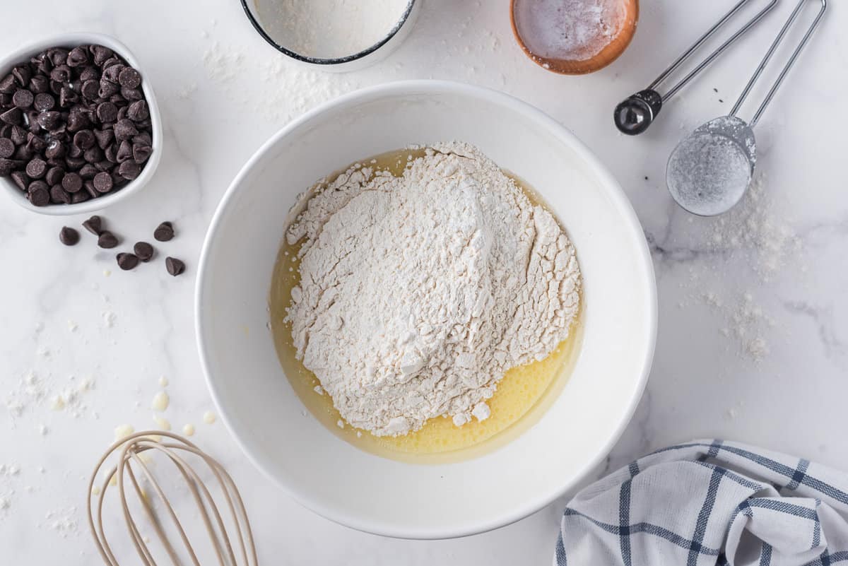 Pancake dry ingredients being added to wet ingredients in white mixing bowl.