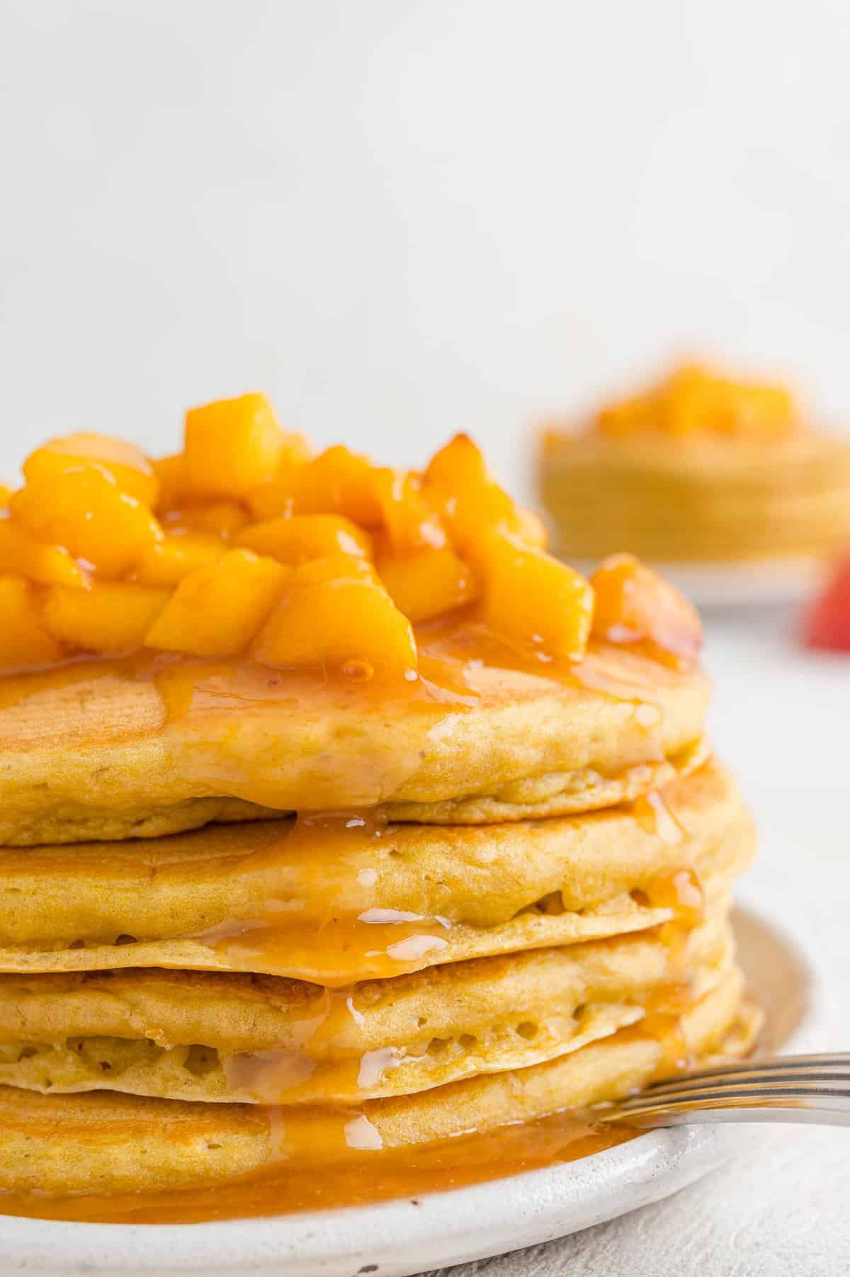 Peach sauce on a tall stack of pancakes.