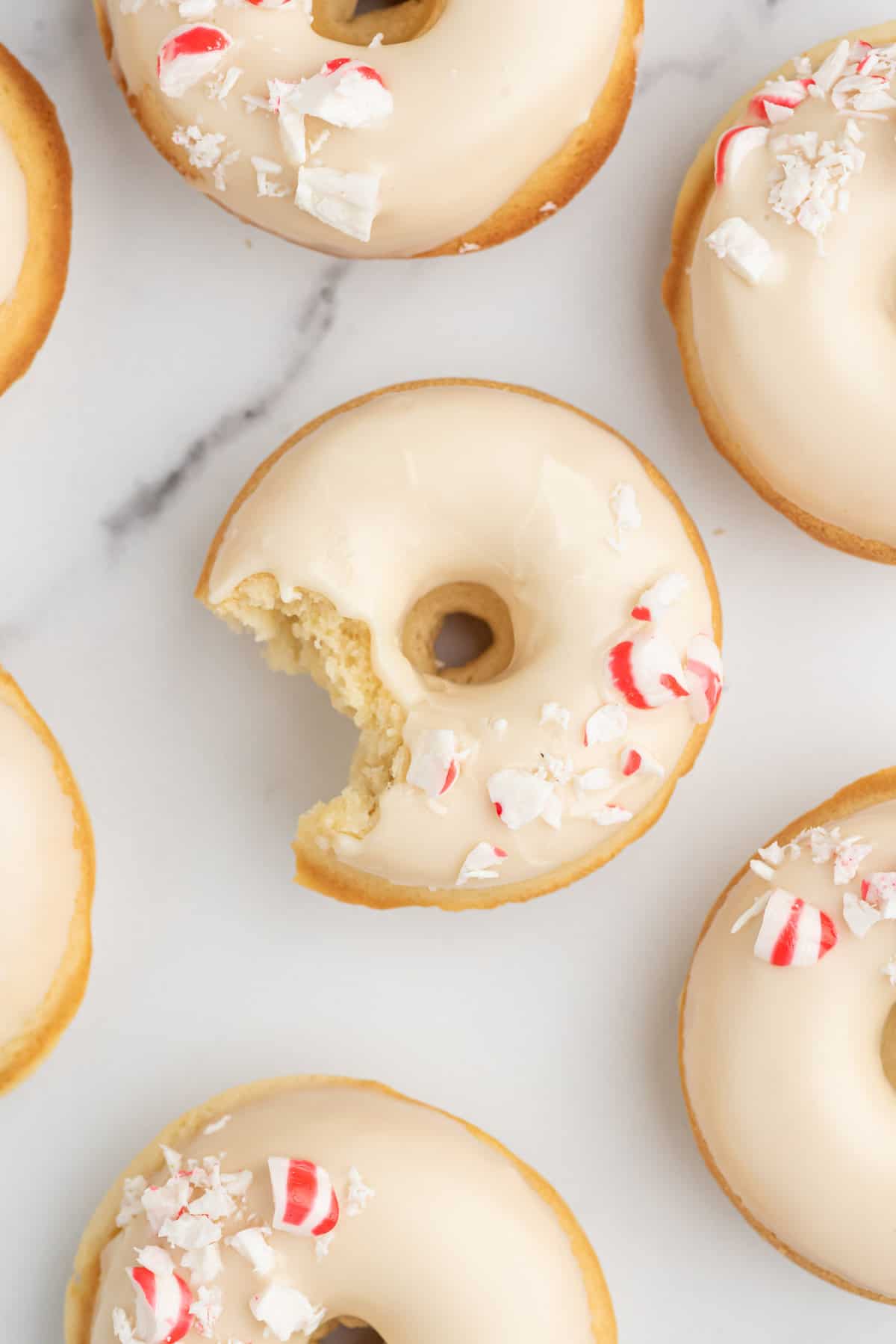 Peppermint donuts, one with a bite out of it.