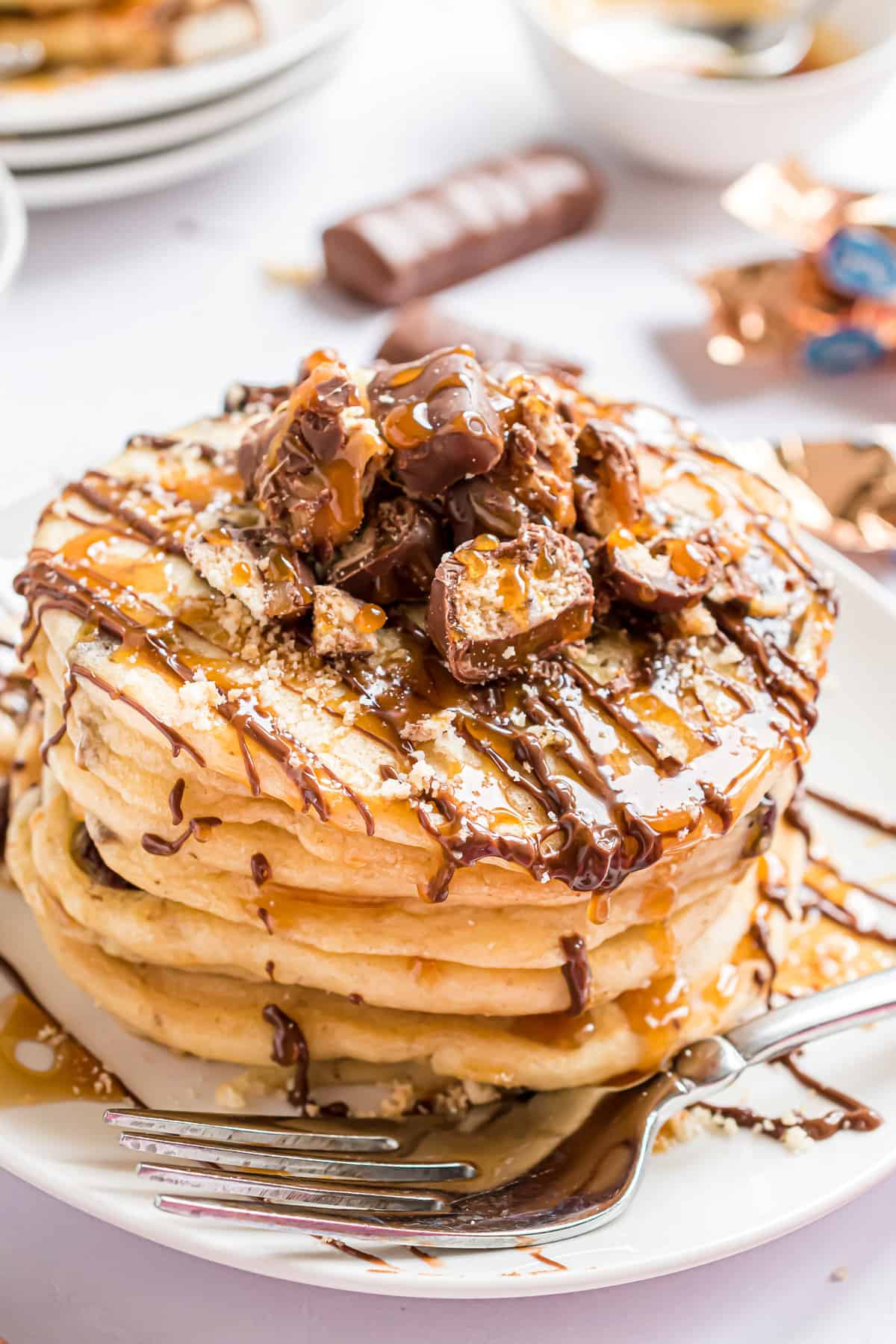 Stack of Twix pancakes with lots of toppings.