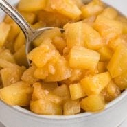 Caramelized pineapple in a bowl with a spoon.