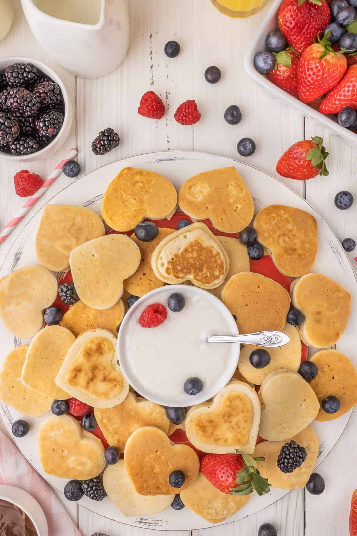 Mini heart pancakes on a platter with fruit.