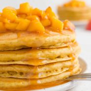 Stack of peach pancakes with peach topping on top.