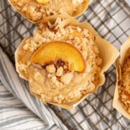Peach streusel muffin topped with fresh peach slice.