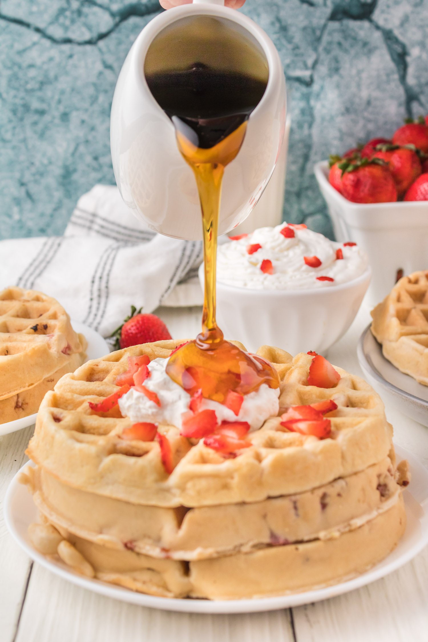 Syrup being poured on waffle.